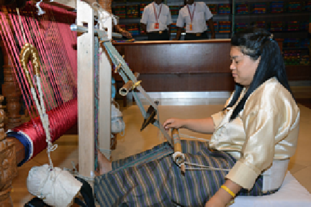 A Bhutanese artisan shows visitors how tigma fabric is woven