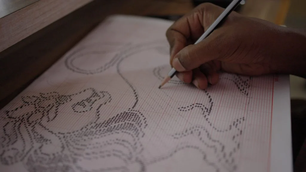 An artist sketches a yazhi motif in minute detail at the RmKV design studio. 